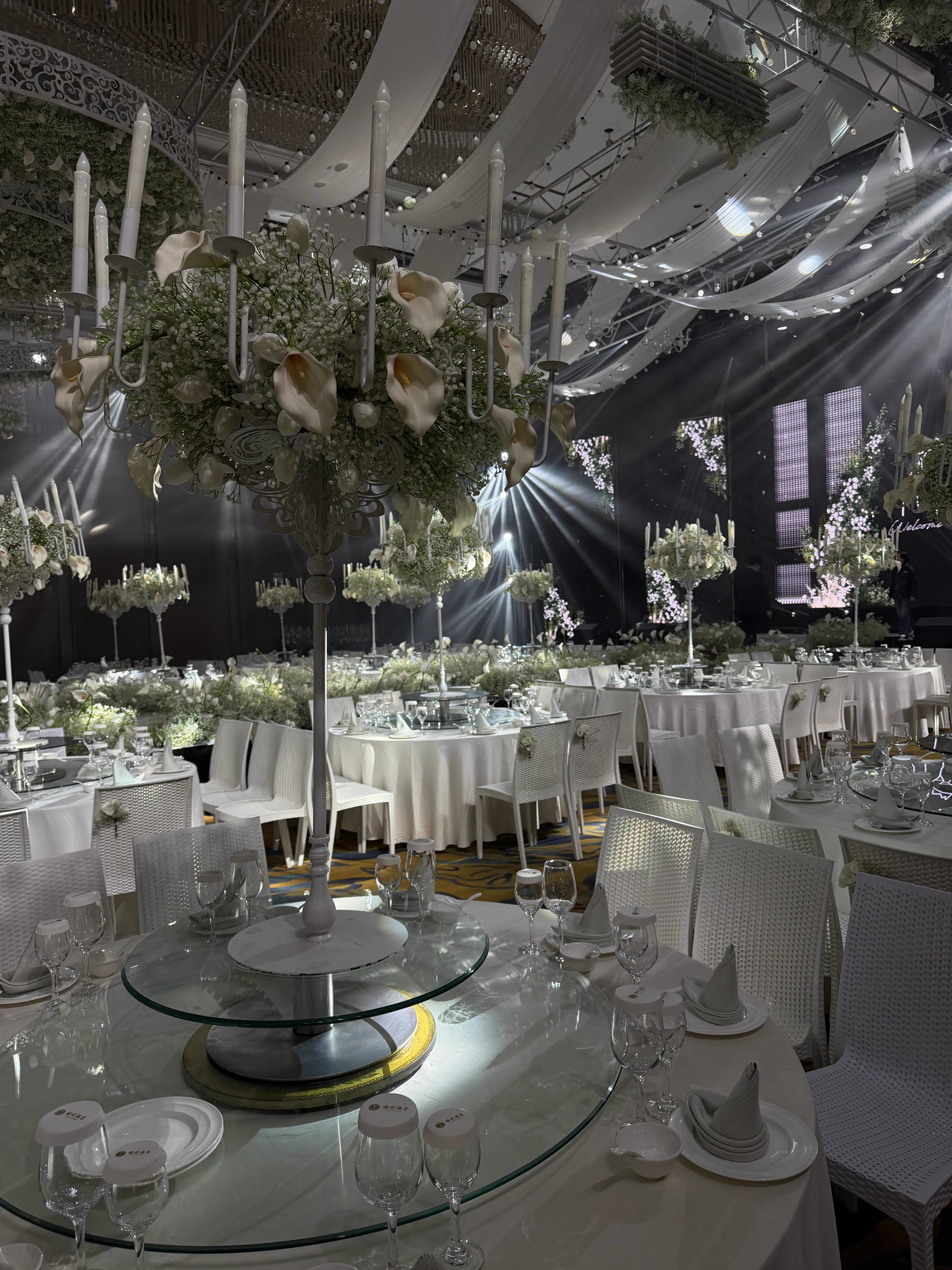 Local ballroom view showing wave-shaped drapes, floral ceiling arrays, and low-profile stage lighting